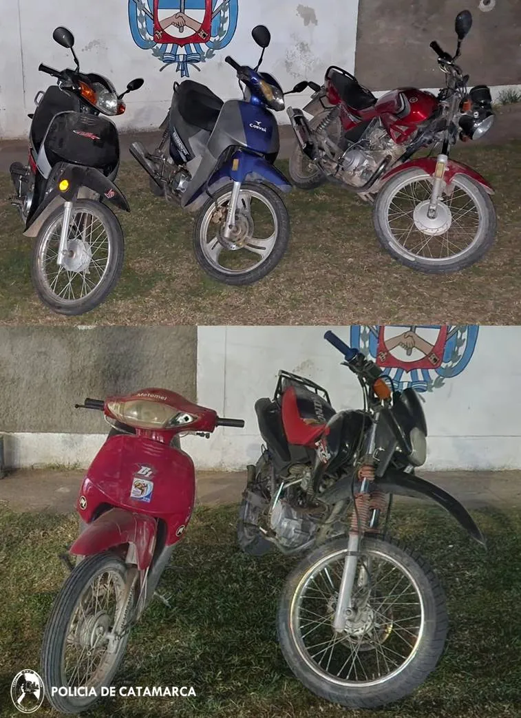 Cinco motos estacionadas frente a una pared blanca con el escudo policial.