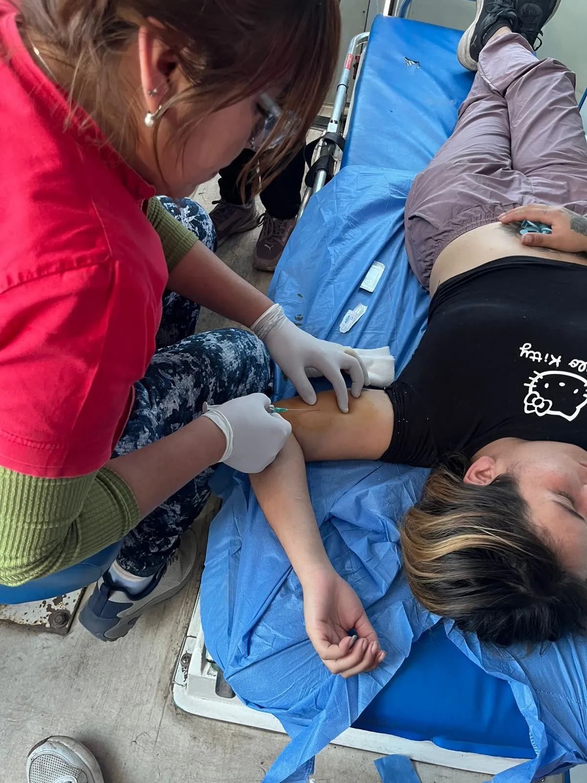 Una profesional de la salud le coloca un implante subdérmico en el brazo a una paciente acostada en una camilla.