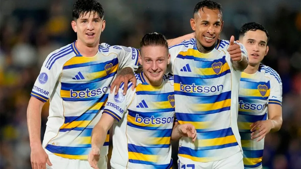 Cuatro futbolistas con la camiseta de Boca festejan sonrientes en la cancha.