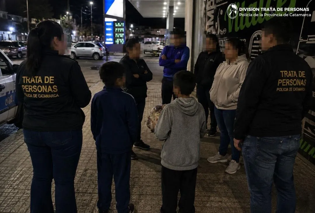 Efectivos policiales y civiles reunidos en la vereda de noche frente a una estación de servicio.