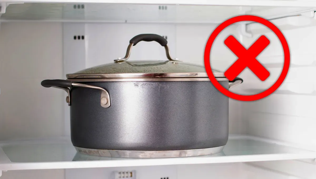 Una olla metálica con tapa de vidrio está dentro de una heladera y tiene superpuesta una cruz roja.