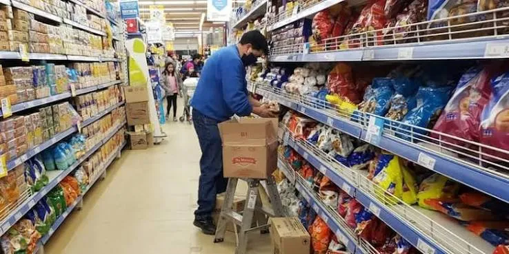 Un empleado acomoda paquetes en las góndolas de un supermercado.