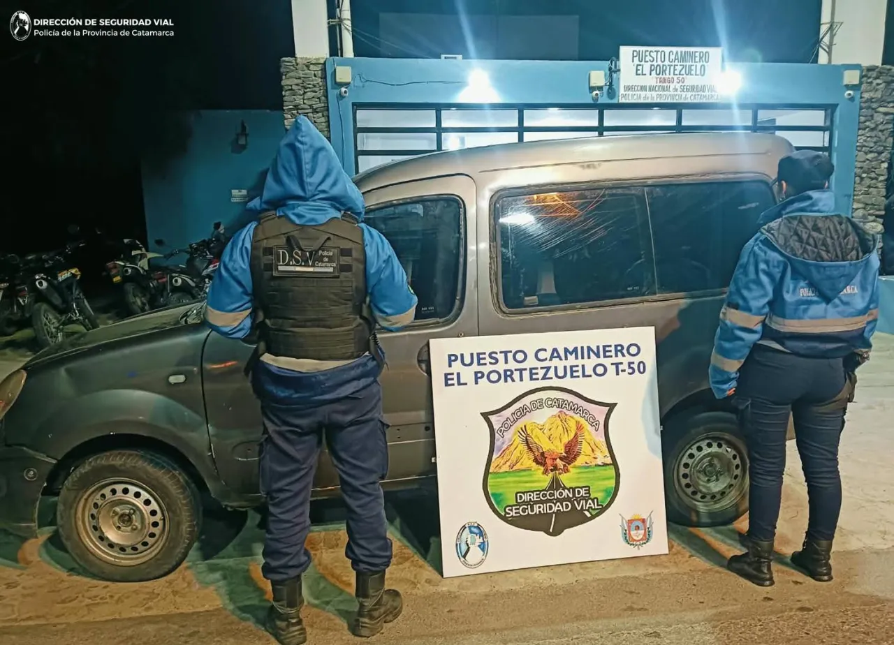 Dos efectivos policiales frente a un utilitario gris estacionado delante del cartel del puesto caminero El Portezuelo.