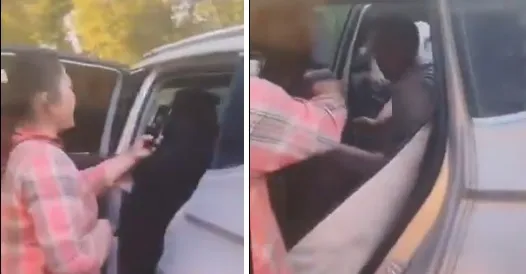 Una mujer con camisa a cuadros filma con su celular a las personas que están dentro de una camioneta.