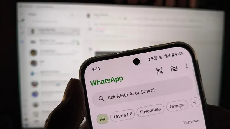 Una persona sostiene un celular que muestra en pantalla la aplicación WhatsApp con la barra de Meta AI.