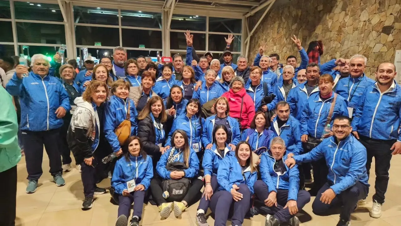 Un grupo numeroso de personas vestidas con camperas deportivas azules posa para una foto grupal.