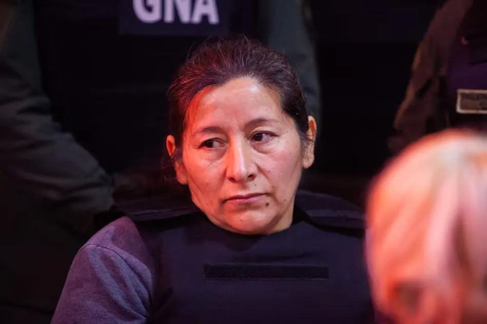 Laudelina vestida con chaleco antibalas ante personal de seguridad.