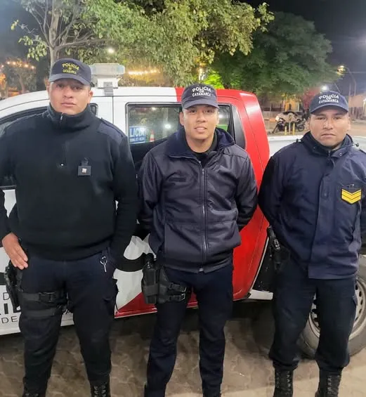 Tres policías uniformados posan parados delante de una camioneta de la Policía de Catamarca.