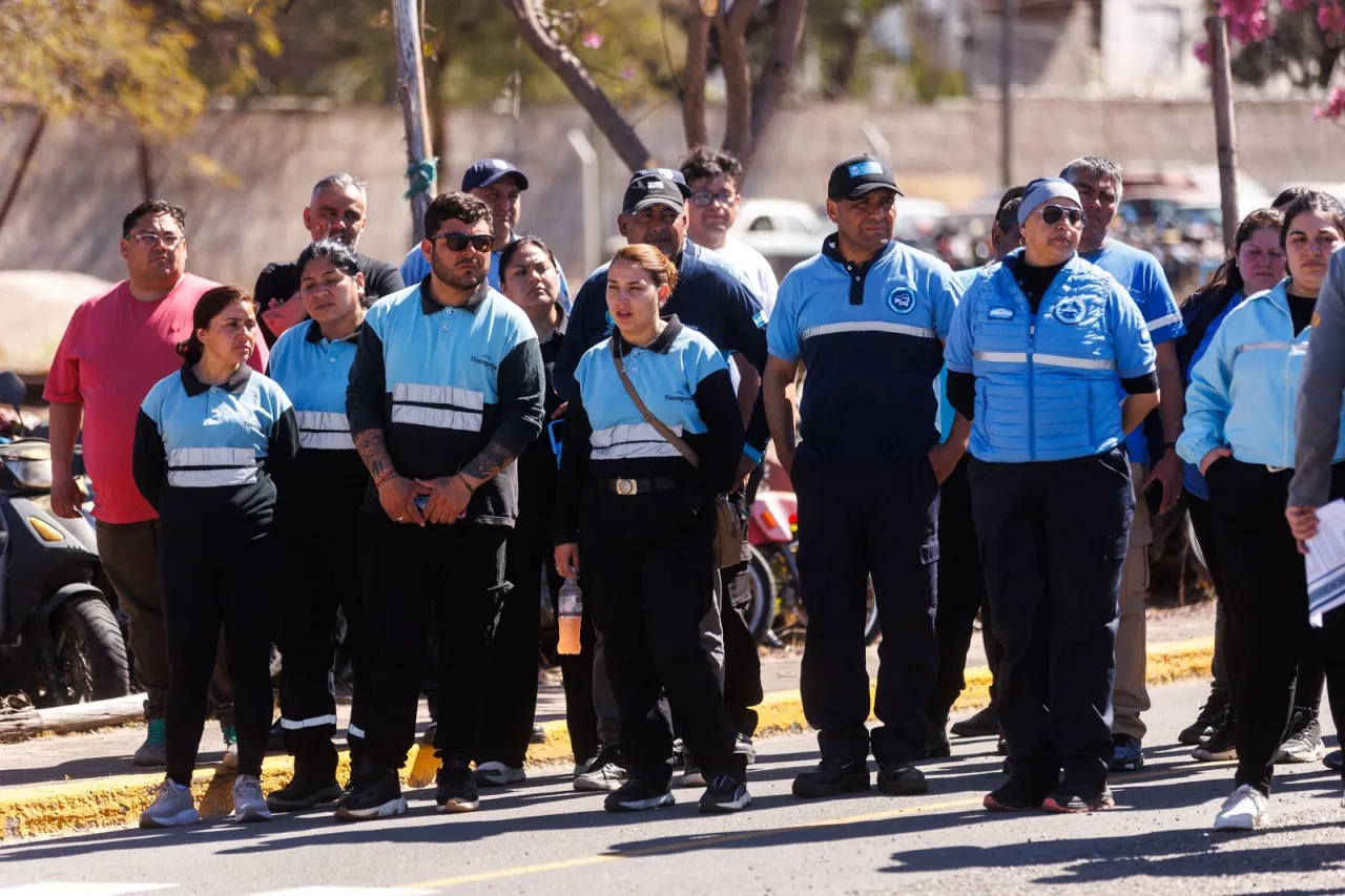 Un grupo de personas con uniformes azules y negros permanece de pie al aire libre.