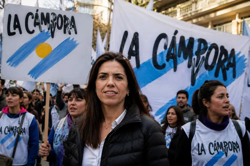 María Soledad Calle camina al frente de una columna que sostiene carteles y banderas con la inscripción La Cámpora.