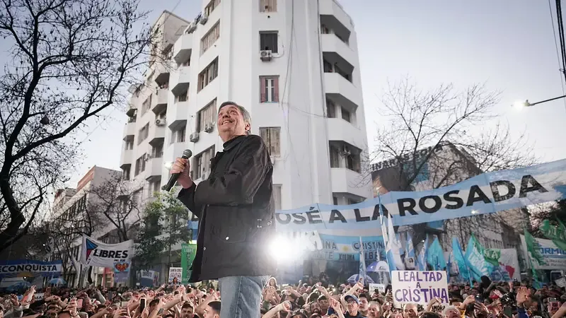 Máximo Kirchner hablando con un micrófono frente a una multitud en la calle.
