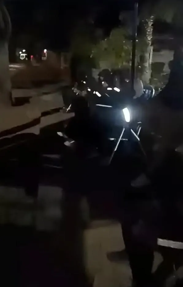 Motocicleta detenida de noche en una calle con las luces encendidas.