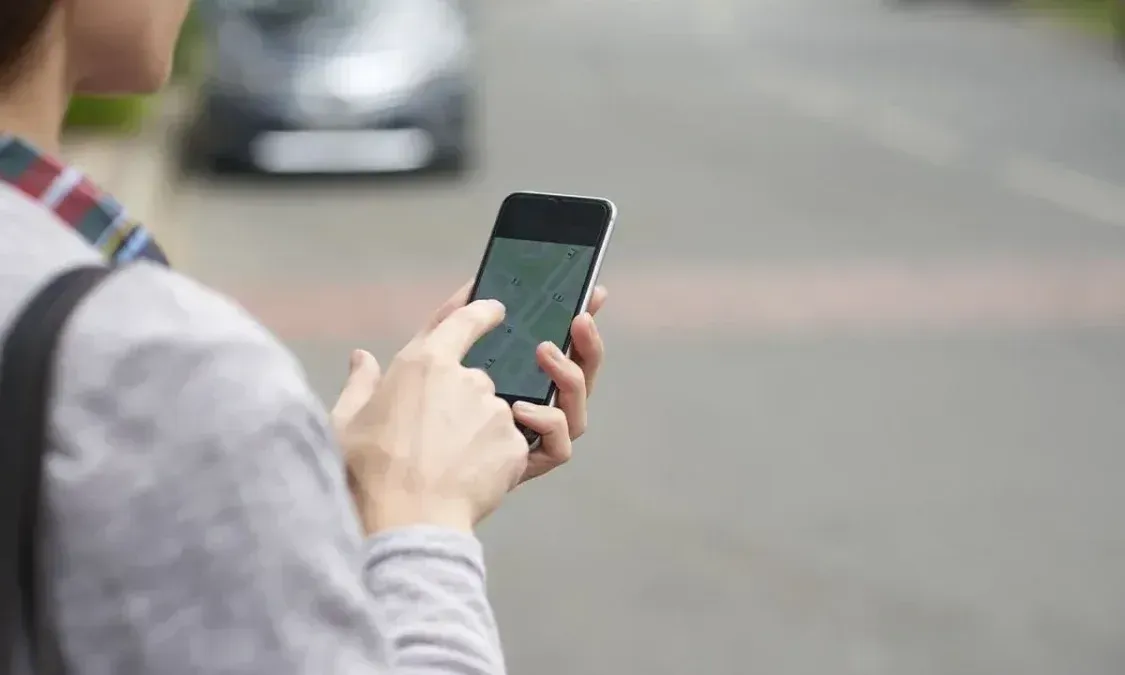 Una persona sostiene un telefono celular con una aplicacion de mapas en la pantalla.