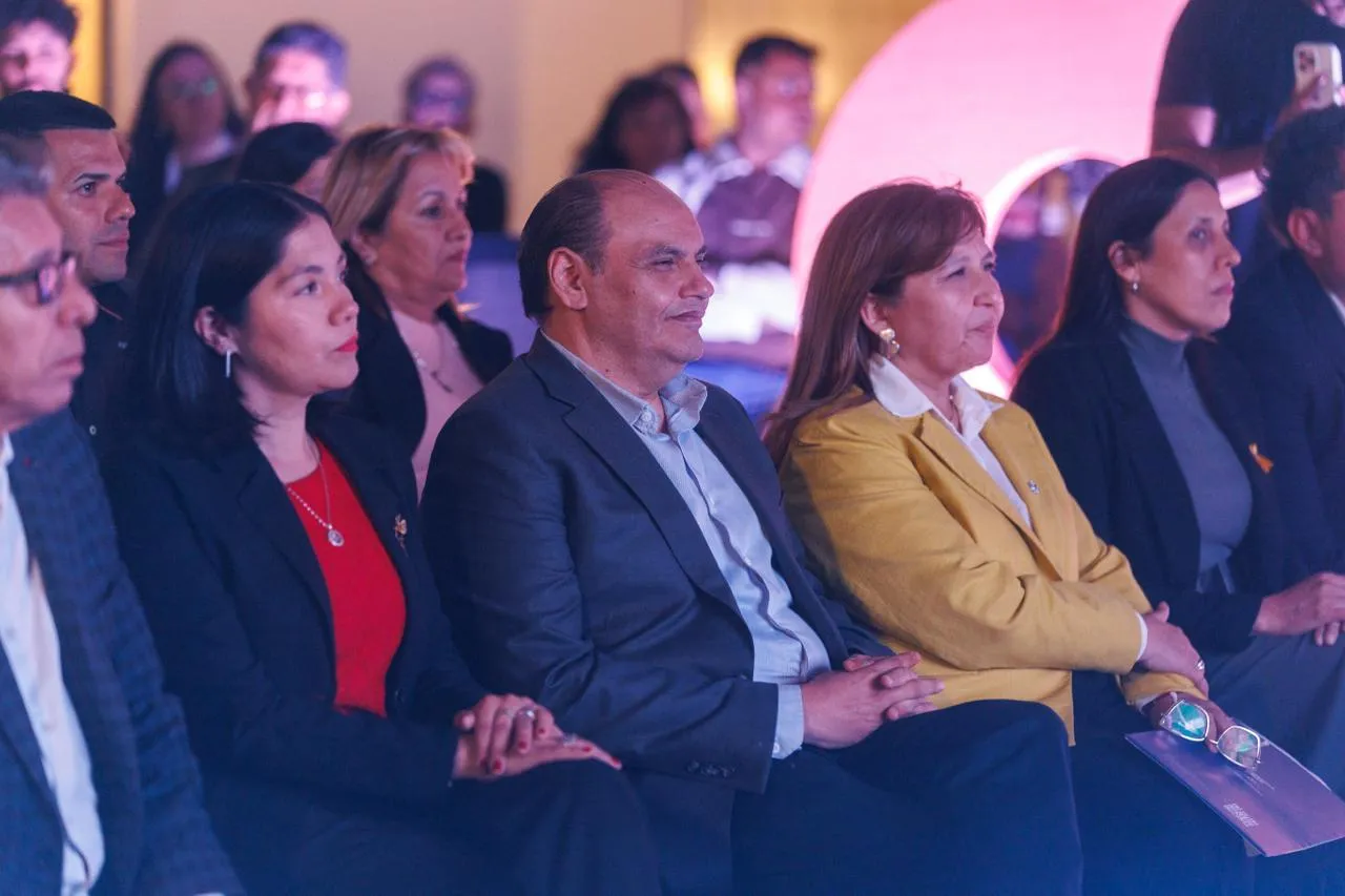 Gustavo Saadi y varias personas sentadas en una platea escuchan un acto.