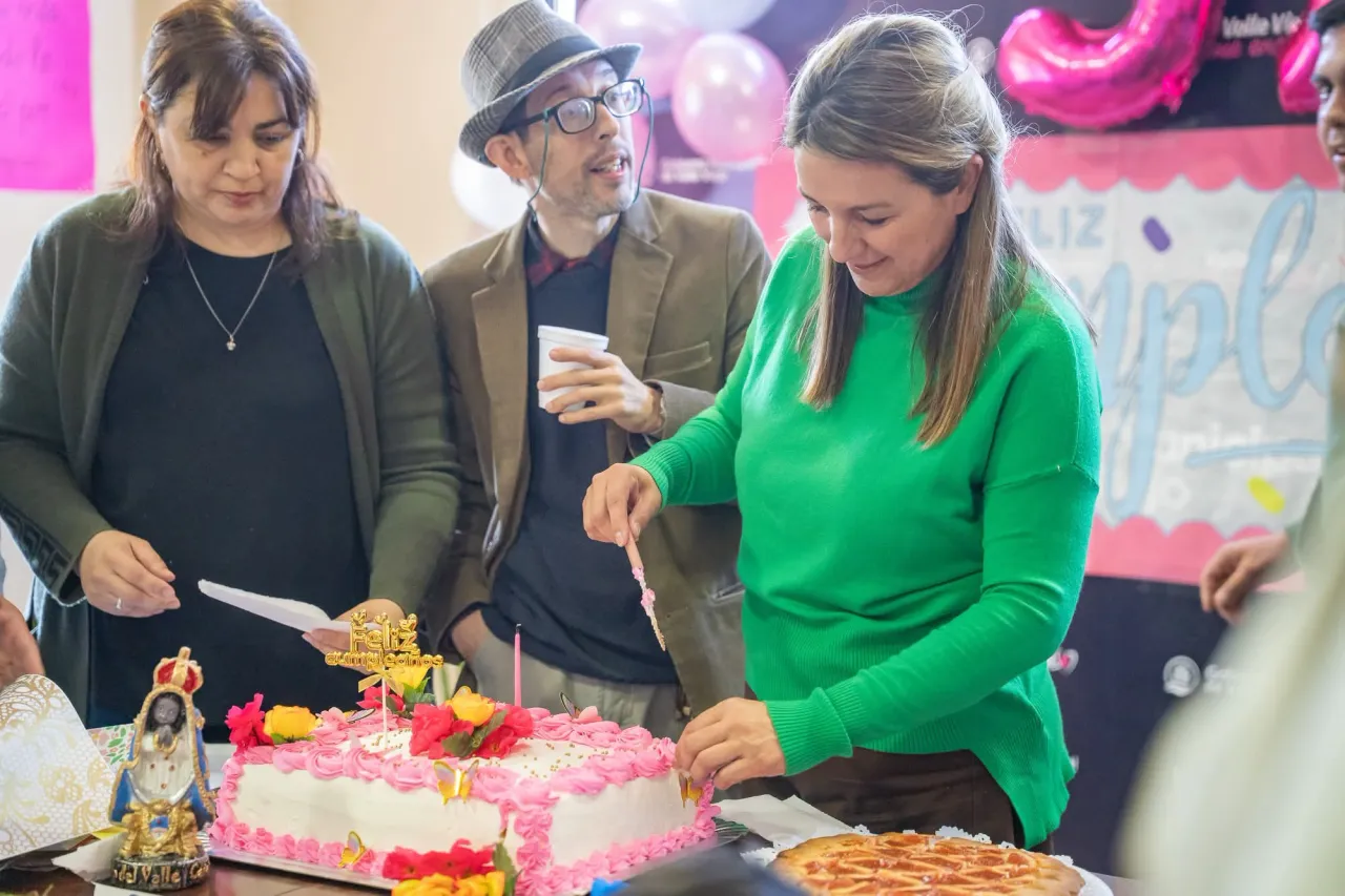 Susana Zenteno corta una torta de cumpleaños frente a varias personas.