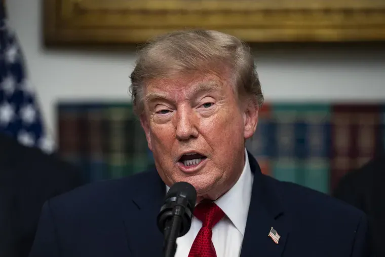 Donald Trump habla frente a un microfono vestido con traje oscuro, camisa blanca y corbata roja.