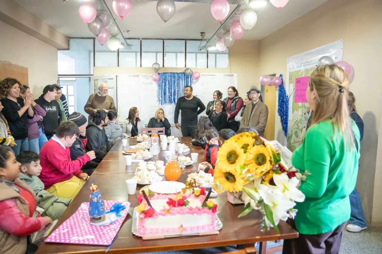 Un grupo de personas reunidas en una oficina decorada con globos alrededor de una mesa con comida.