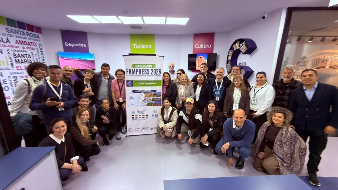 Un grupo numeroso de personas posa de pie y arrodilladas en una sala junto a un banner de Fampress 2026.