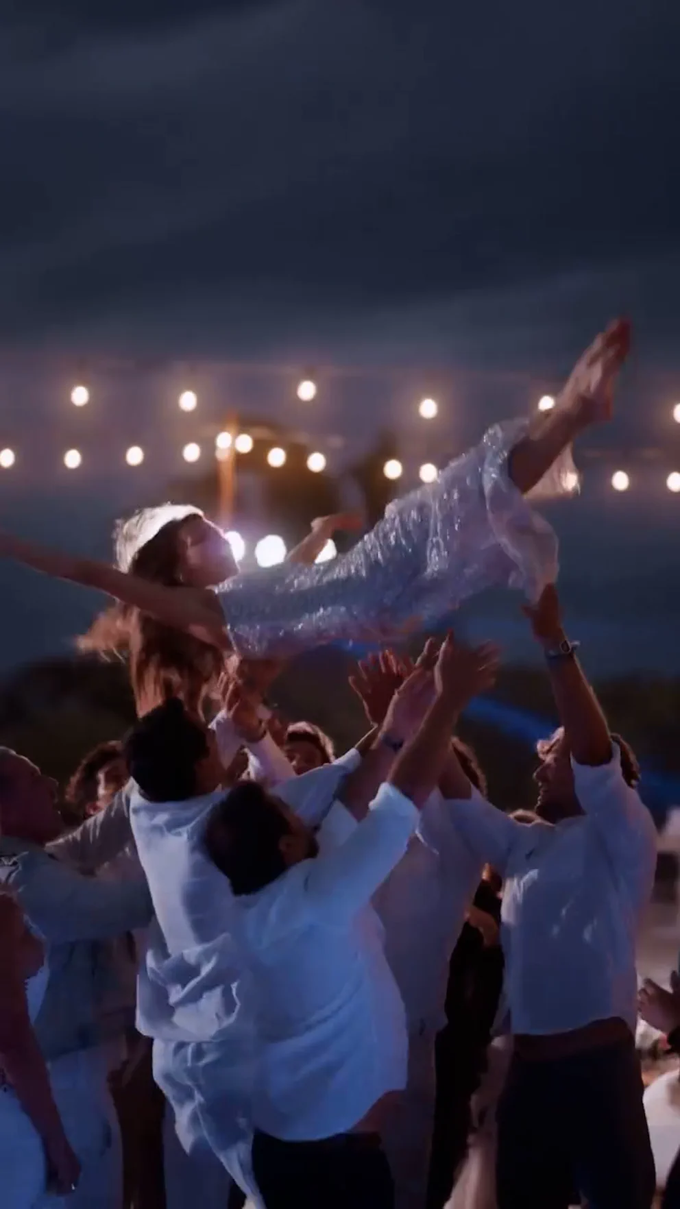 Varios hombres levantan por el aire a Pampita, que lleva un vestido brillante, durante una fiesta nocturna.