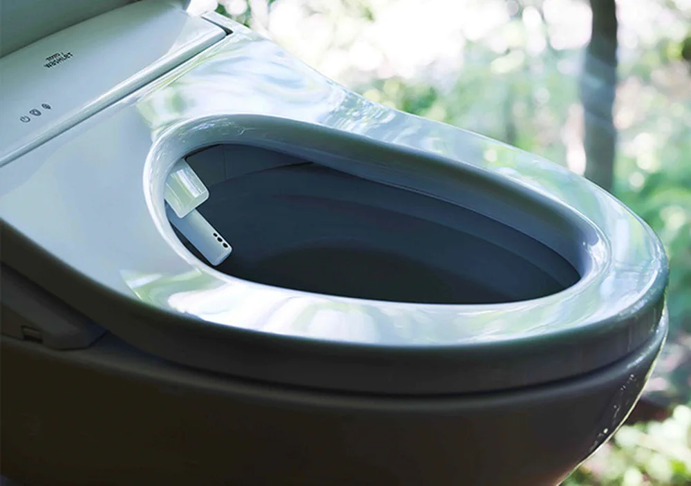 El asiento abierto de un inodoro inteligente tiene una boquilla extensora incorporada.