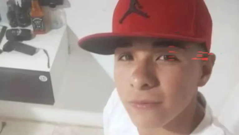 Un joven con gorra roja y remera blanca mira fijamente a la camara.