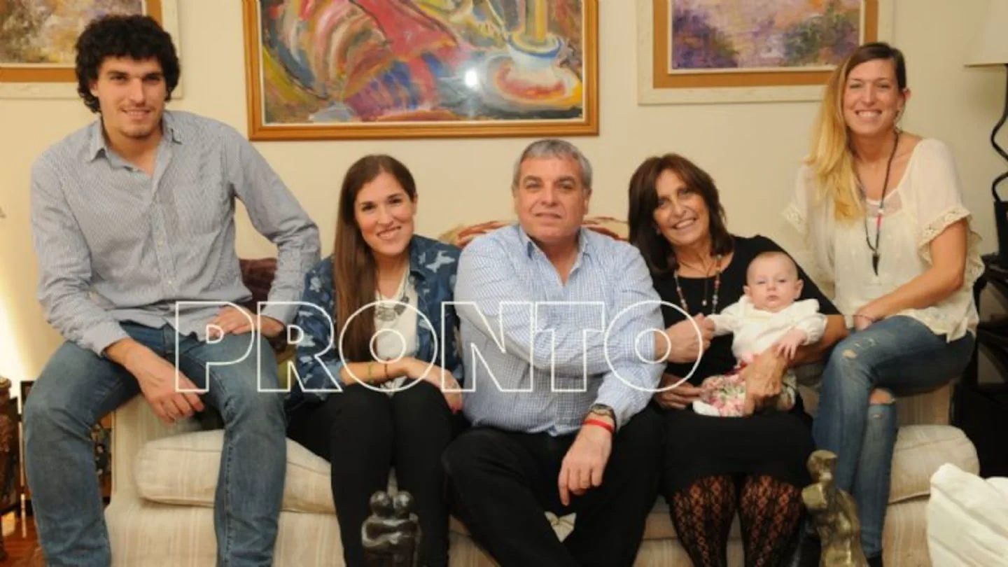 Carlos Monti junto a su familia sentados en un sillón blanco posando para un retrato.