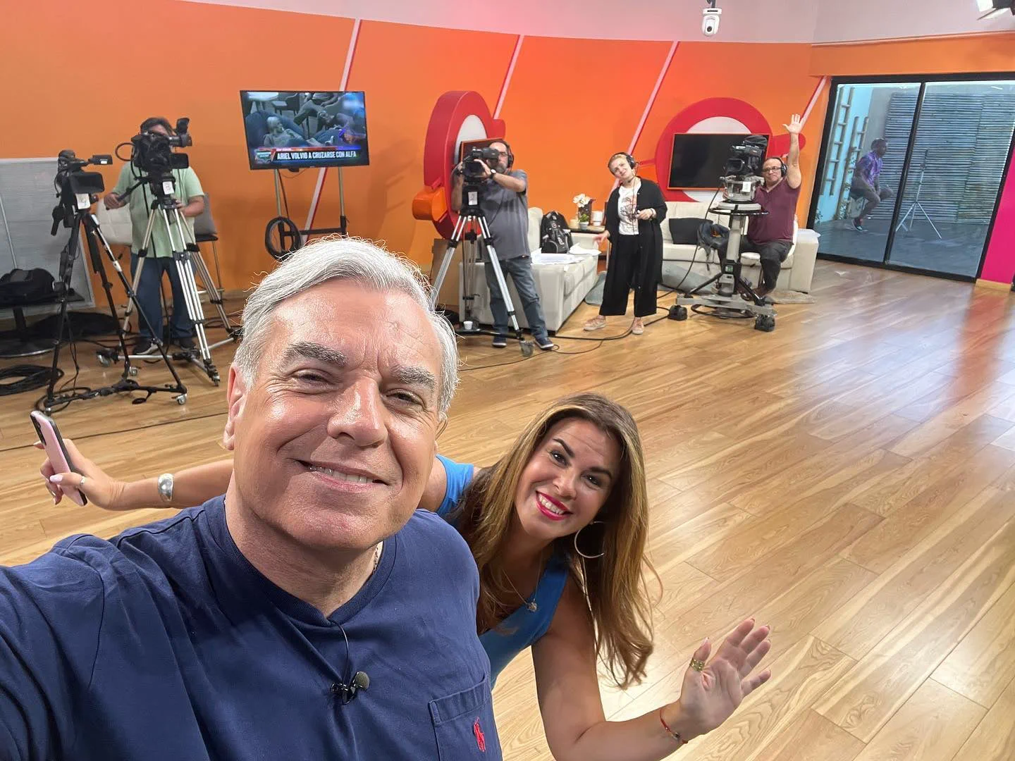 Carlos Monti se saca una selfie sonriendo en un estudio de televisión junto a una compañera y el equipo técnico.