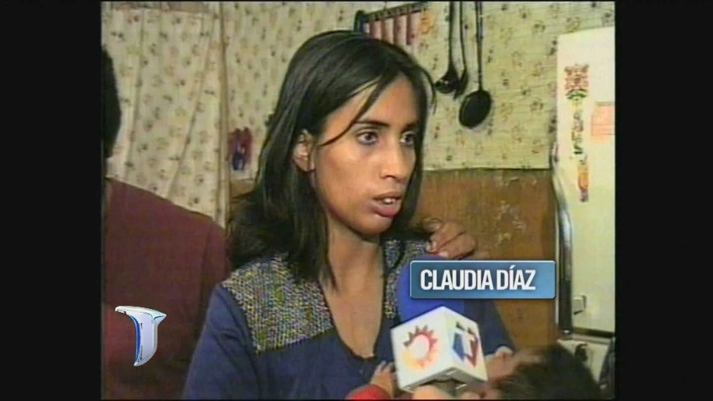 Una mujer llamada Claudia Díaz habla frente a un micrófono de televisión sosteniendo a un bebé.
