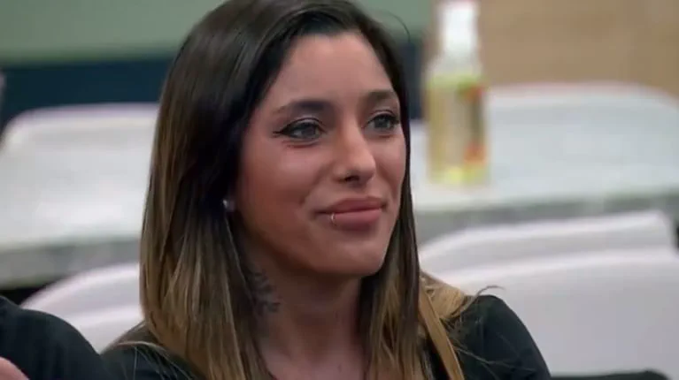 Primer plano de una mujer de pelo castaño claro y un piercing en el labio sonriendo hacia un costado.