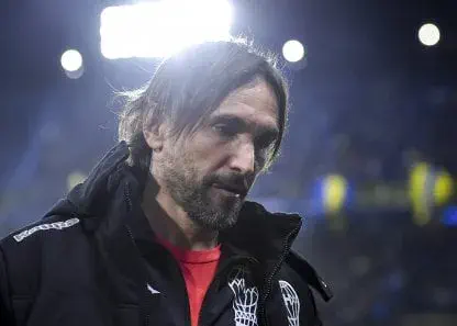 Diego Martínez mira hacia abajo vestido con una campera deportiva negra del club Huracán.