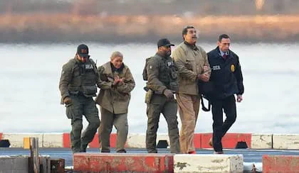 Efectivos de seguridad escoltan a varias personas que caminan sobre una pista.
