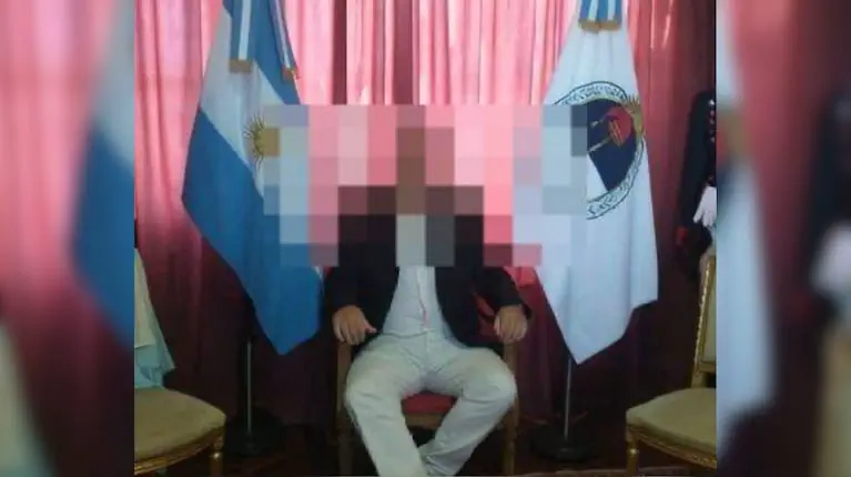 Una persona sentada con el rostro pixelado entre la bandera argentina y la bandera de Catamarca.