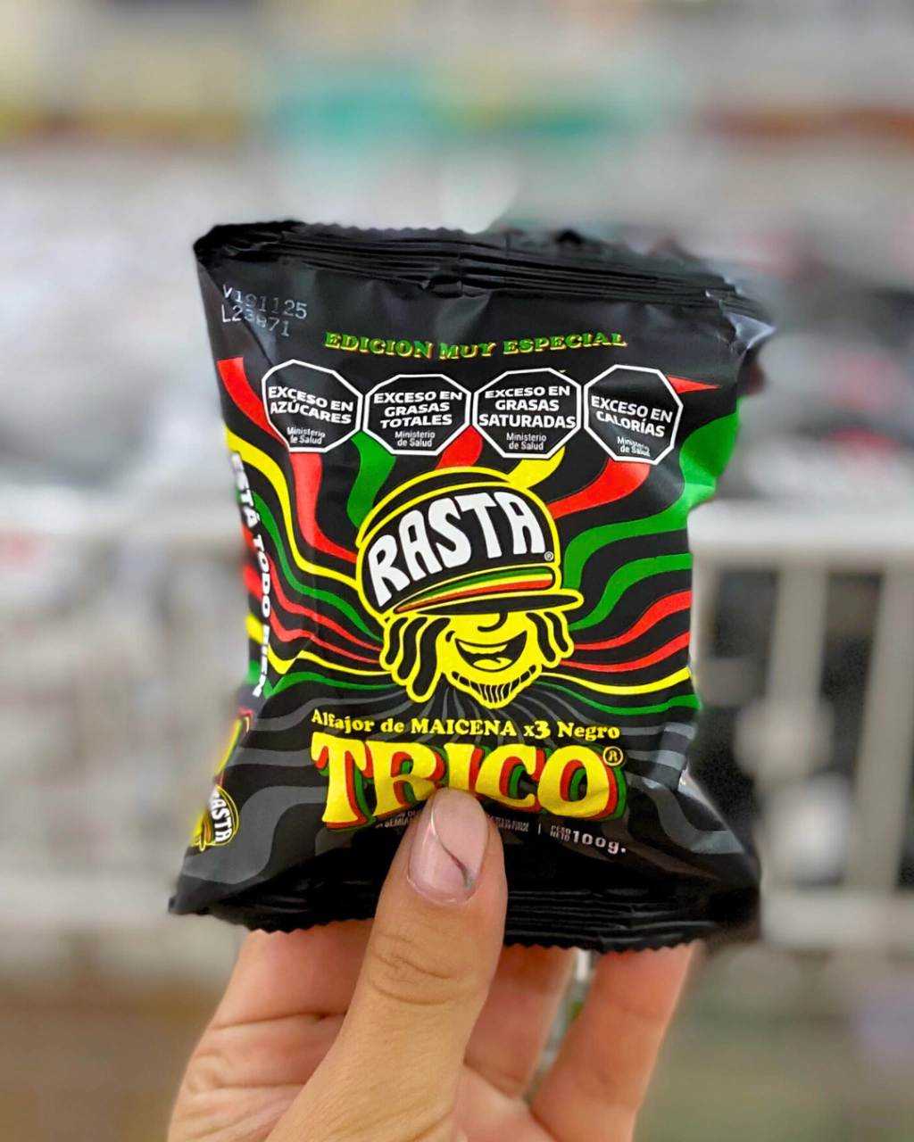 Una mano sostiene un paquete de alfajor de maicena triple Rasta edición especial.