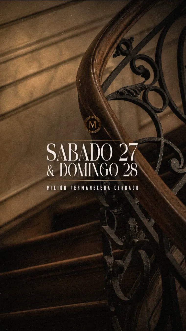 Escalera antigua con baranda de hierro forjado y un cartel anunciando el cierre del bar Milión.