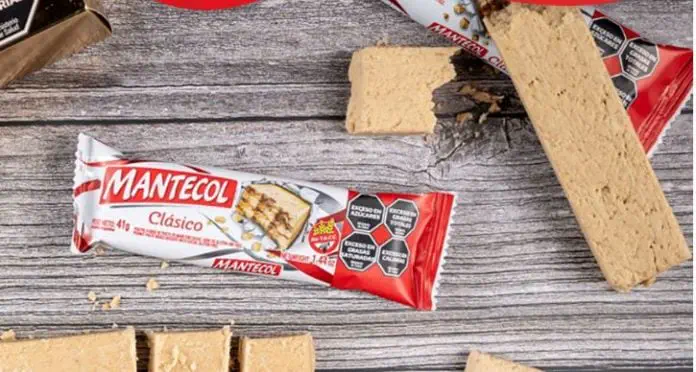 Un paquete de turrón Mantecol junto a varios trozos del dulce cortados sobre una mesa de madera.