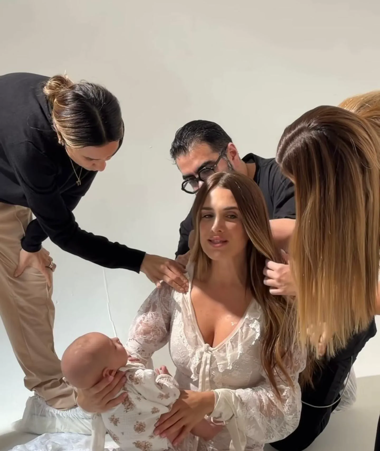 Camila Homs con un bebé en brazos asistida por estilistas durante una sesión de fotos.