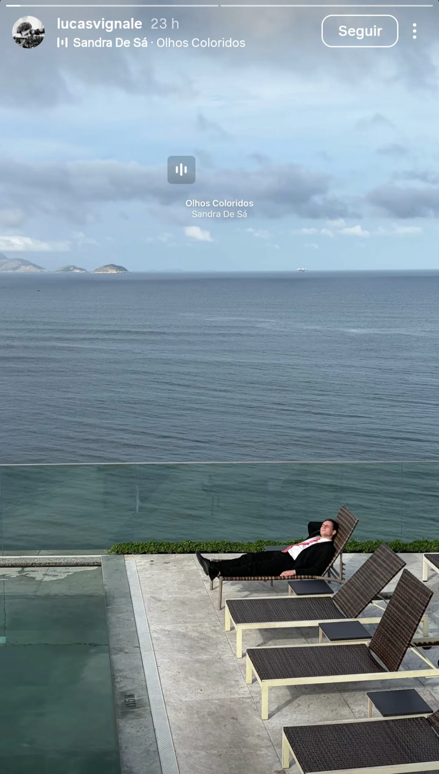 El director Lucas Vignale descansa de traje en una reposera al lado de una pileta frente al mar.