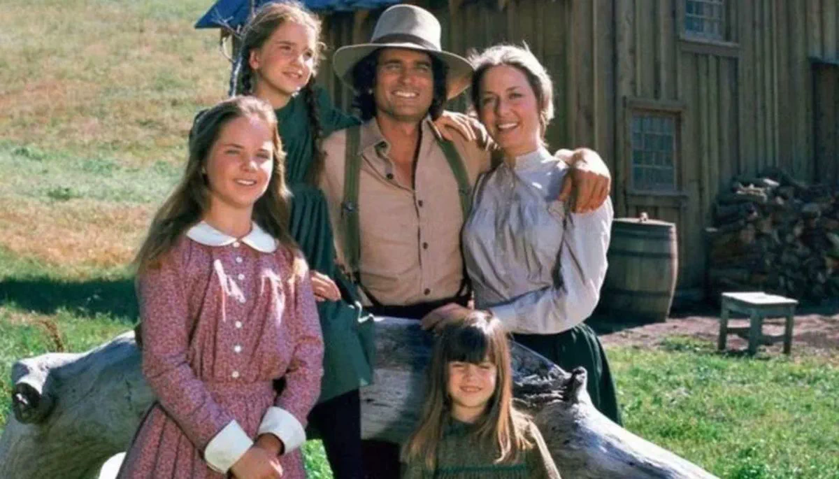 El elenco de la familia Ingalls de La familia Ingalls posando al aire libre junto a una cabaña.