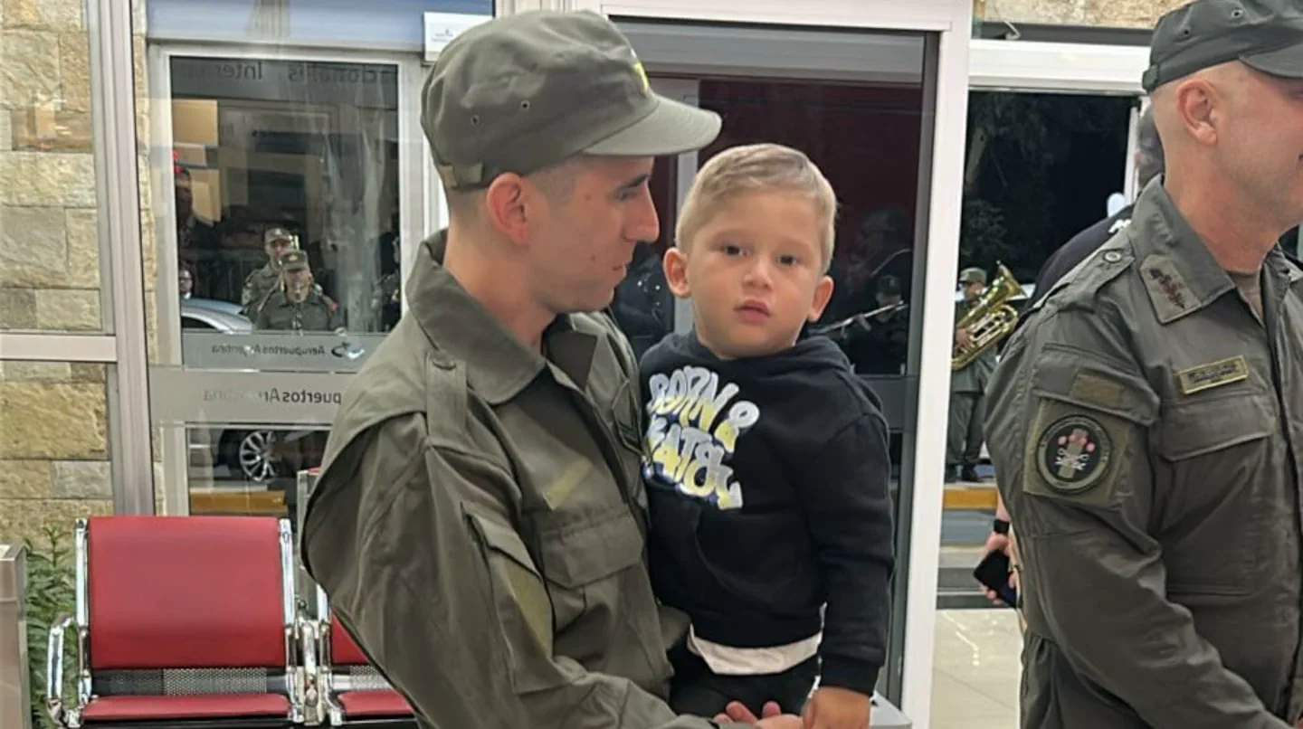 Un efectivo de Gendarmería Nacional sostiene a un nene a upa en una sala de espera.