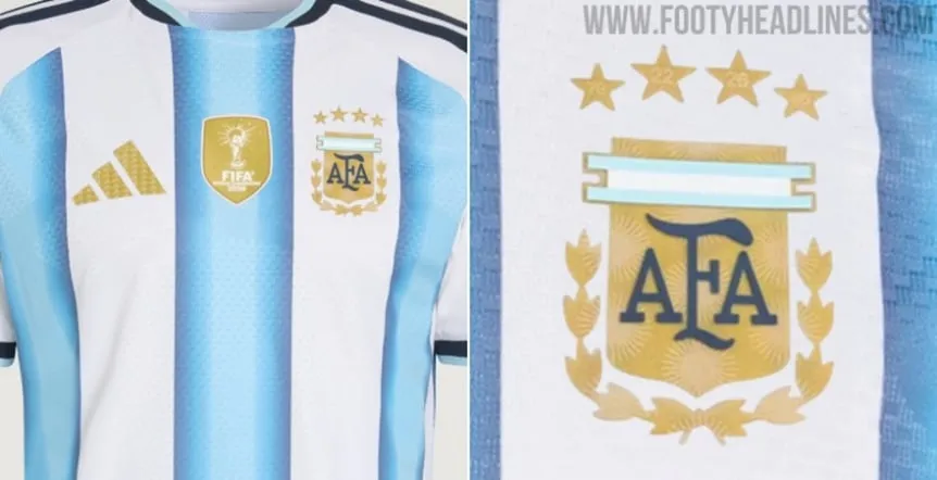 Detalle del escudo dorado de la AFA con cuatro estrellas y parche de campeón en una camiseta argentina.