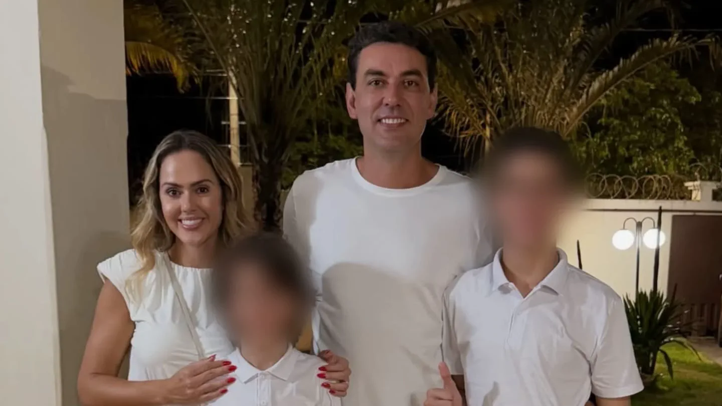 Un hombre y una mujer posan de noche junto a dos chicos que tienen sus caras borrosas.