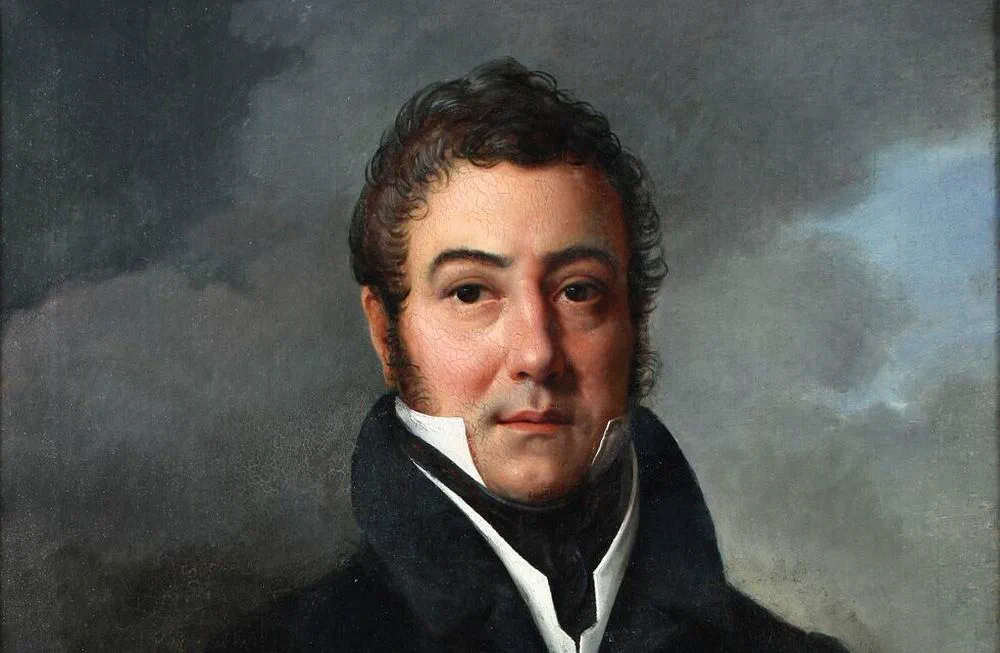 Retrato al óleo de José de San Martín con abrigo oscuro de cuello alto y camisa blanca.