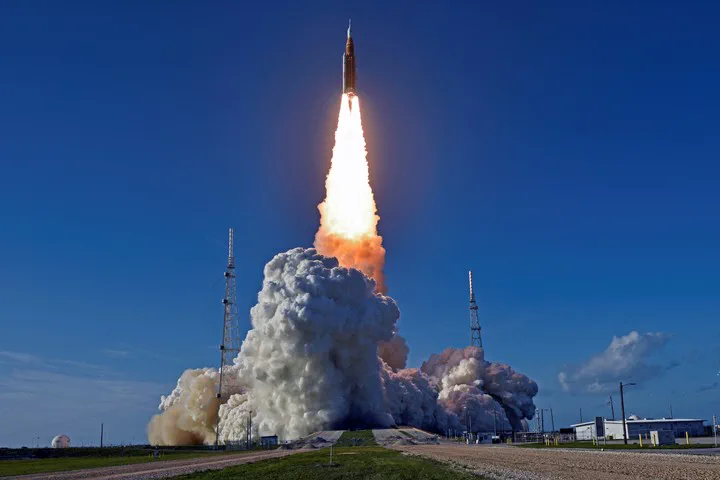 Un cohete espacial despega verticalmente dejando una densa columna de humo y fuego sobre la plataforma de lanzamiento.