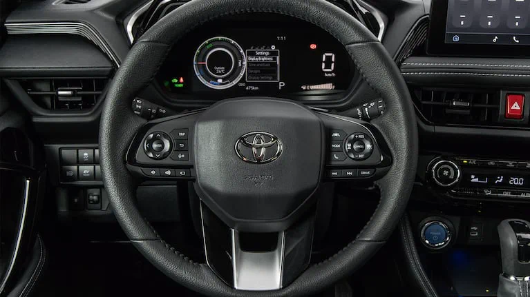 Volante y tablero digital de un vehículo Toyota con comandos de control e instrumental encendido.