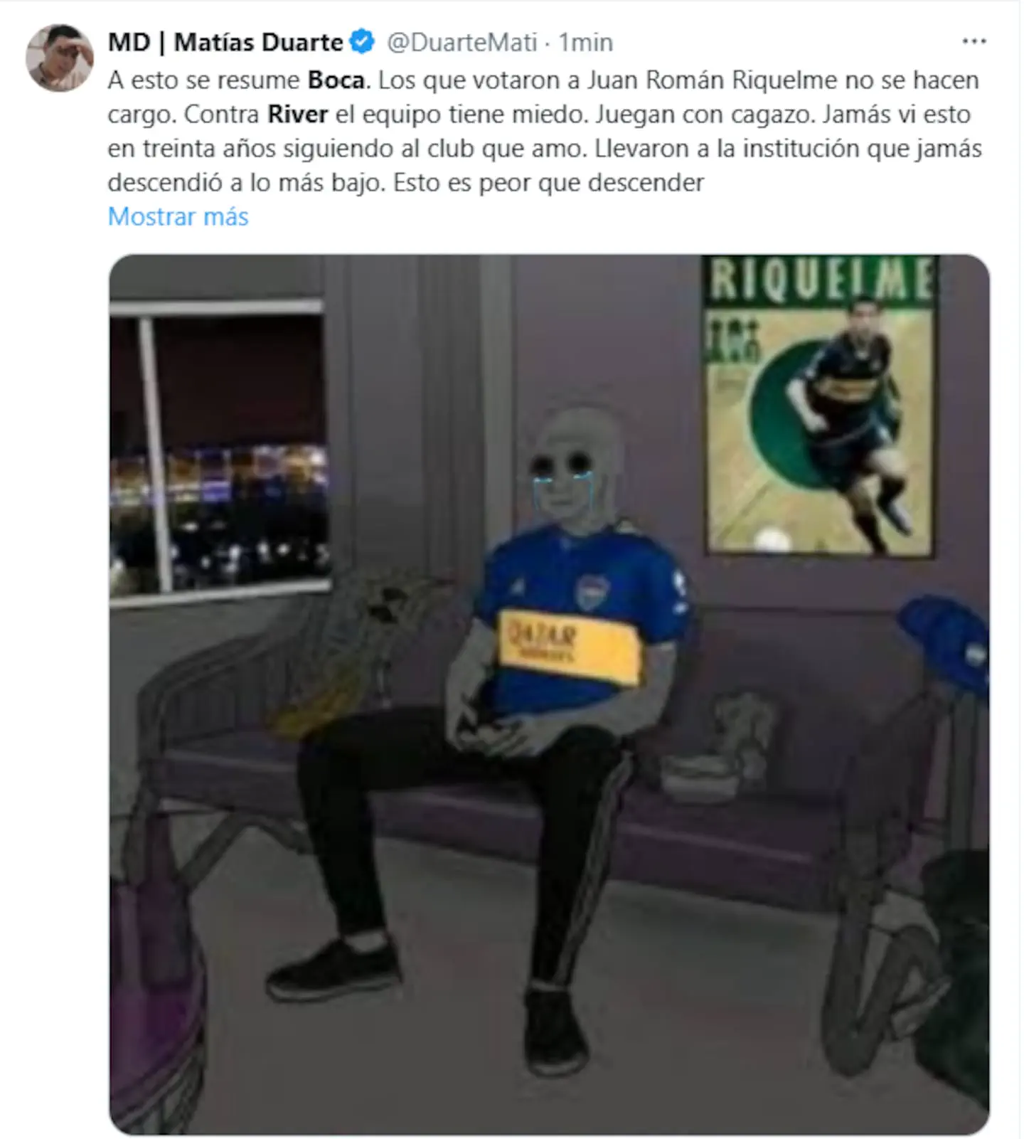Un personaje animado llora sentado en un sillon con la camiseta de Boca Juniors en una habitacion.