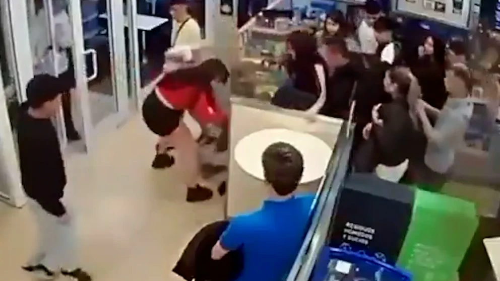 Varias personas en un local de comida rápida frente al mostrador y la puerta de entrada.