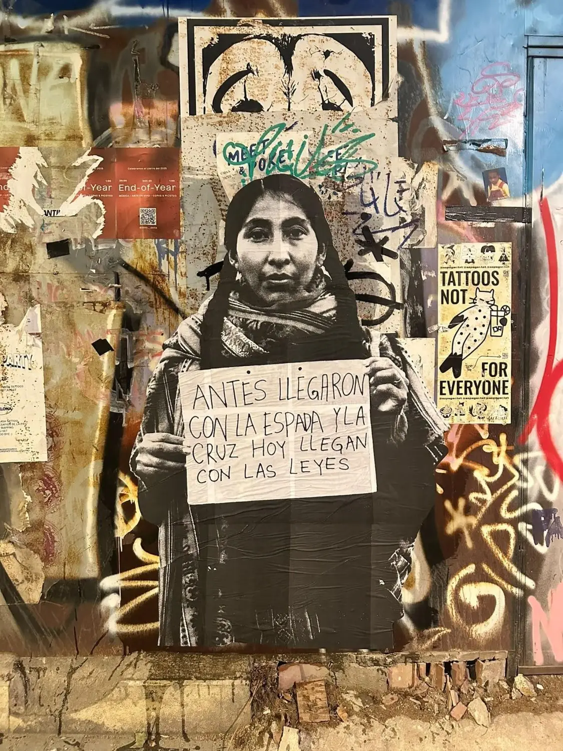 Afiche pegado en una pared con la imagen de una mujer sosteniendo un cartel con un mensaje manuscrito.