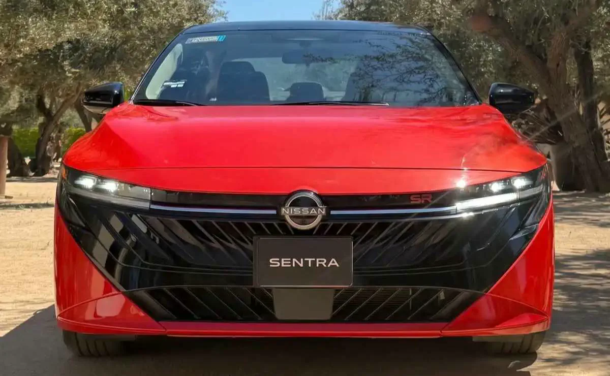 Frente de un auto rojo marca Nissan modelo Sentra estacionado al aire libre.