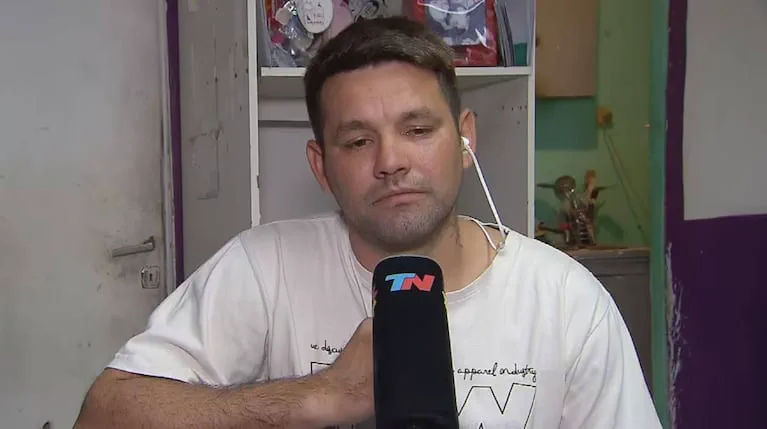 Un hombre con remera clara tiene puesto un auricular y habla frente a un micrófono de TN.