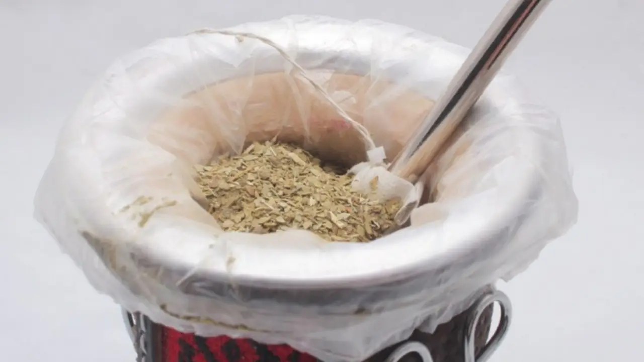 Mate con bombilla y yerba cubierto en el borde por un plástico transparente.
